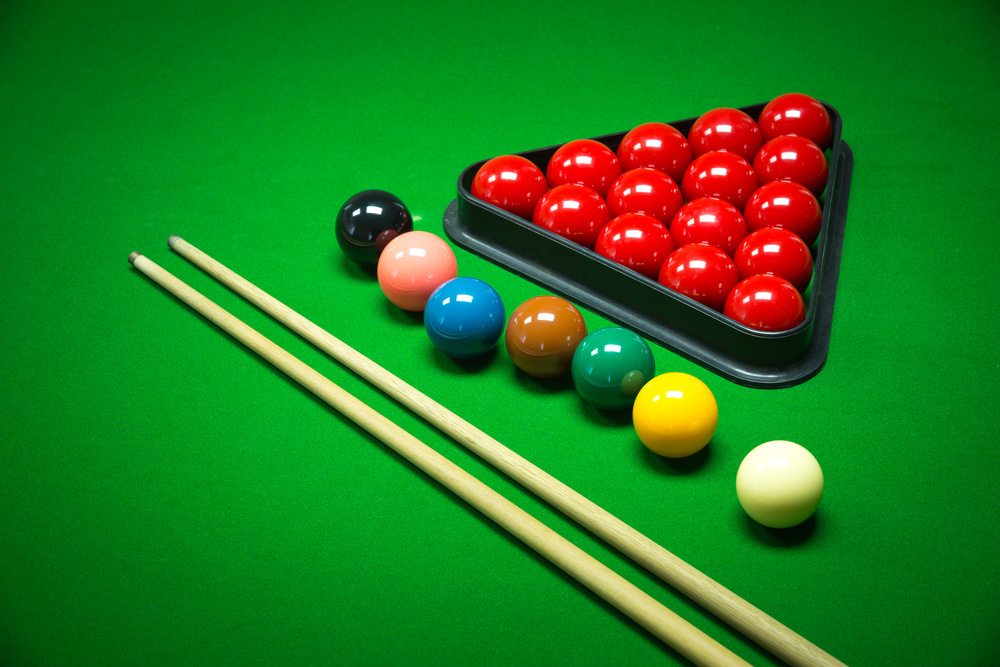Snooker balls and cues on a green baize table